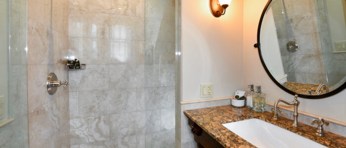 Room 10 Bathroom Granite Vanity Sink with Mirror Glass Enclosed No-Curb Shower with Large Porcelain Tile.