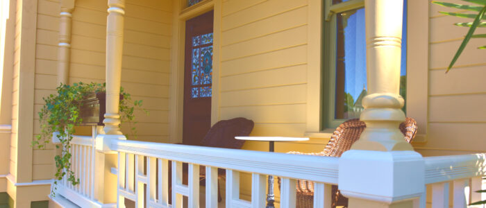 Room 10 Large Historic Front Porch with Eastlake Style Balustrade and Railing Now Wide Balcony with 2 Wicker Chairs and Marble Topped Table