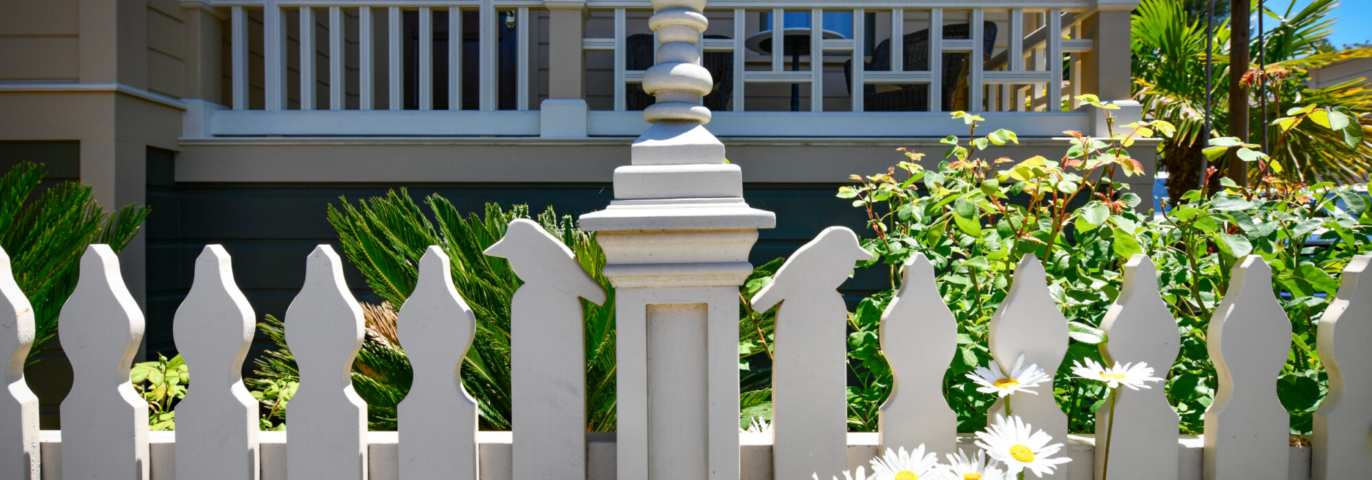 Room 10 Parch/Balcony with Garden In Front, Showing Detail of Picket Fence Having Traditional Eastlake Details and Added Bird Topped Pickets.