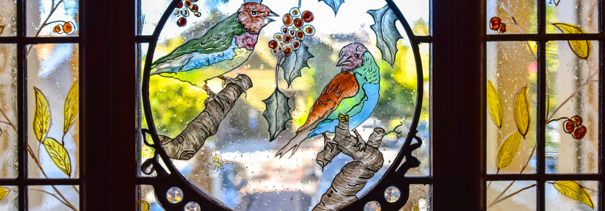 A Stained Glass Detail from The Finch Guest House's Front Door Features Hand-Painted Birds and Plants.