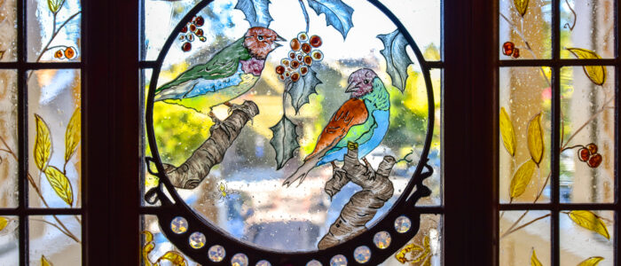 A Stained Glass Detail from The Finch Guest House's Front Door Features Hand-Painted Birds and Plants.