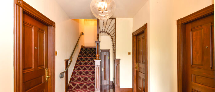 The Finch Guest House Lobby has Granite Floors, Dark Wood, and Eastlake Styled Fretwork. A Private Staircase Leads to Room 12 Which Occupies the Entire 2nd Floor of the Building.