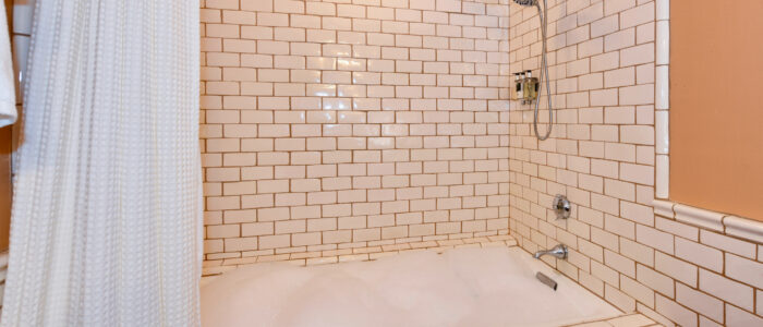 Room 4 Combination Shower and Jacuzzi Jetted Tub. Subway Tile on shower walls, foam covers water in tub.