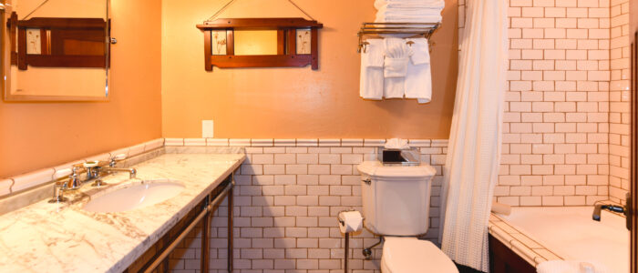 Room 8 Bathroom Shower Combination with Jetted Jacuzzi Tub, Toilet, Towels on Wall Rack, Wide Marble Counter with Sink and Vanity Mirror