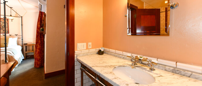 Room 8 Bathroom, Wide Marble Counter with Sink and Vanity Mirror, Doorway Open to Bedroom