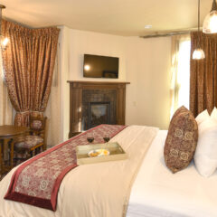 Room 9 King Bed, Fireplace and Flat Screen TV. Alcove Opposite Bed has Chandelier, 2 Chairs and Table.