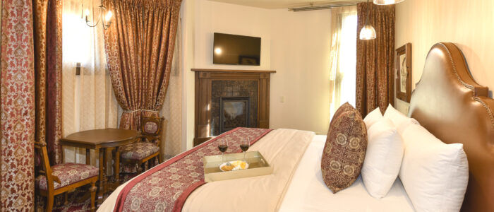 Room 9 King Bed, Fireplace and Flat Screen TV. Alcove Opposite Bed has Chandelier, 2 Chairs and Table.