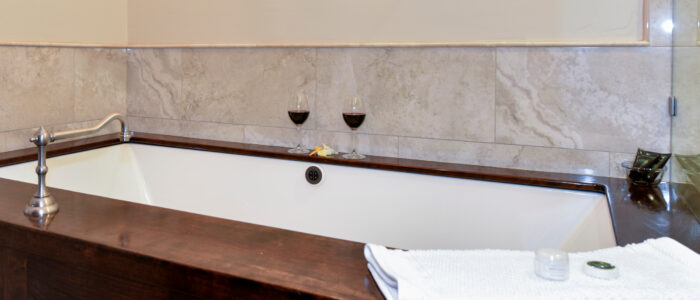 Room 9 Bathroom Champaign Bubble Tub with Towel and 2 Glasses of Red Wine on Sides