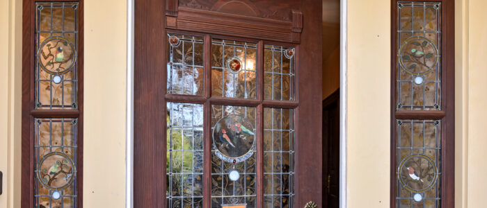 Front Door of Finch Guest House with Sectioned Stained Glass in Door and Fixed Satin Glass Panels on Sides have English Garden Them with Bird and Flowers